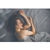 Pretty, young woman sleeping in her bed late in the morning on a weekend - compensating for the lack of sleep