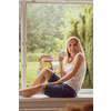 Mid-aged woman enjoying a cup of coffee in a window of her appartment