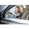 Pretty, middle aged woman vacuum cleaning the interior of a luxury car