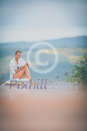 Young Beautiful Suntanned Woman wearing sunglasses relaxing next to a Swimming Pool on a lovely Summer Day Young Beautiful Suntanned Woman wearing sunglasses relaxing next to a Swimming Pool on a lovely Summer Day