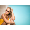 Young Beautiful Suntanned Woman wearing sunglasses relaxing next to a Swimming Pool  on a lovely Summer Day