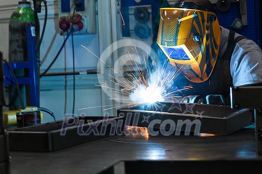 Professional welder performs work with metal parts in factory, sparks, and electricity. Industry worker banner. High quality photo Professional welder performs work with metal parts in factory, sparks, and electricity. Industry worker banner. High quality photo