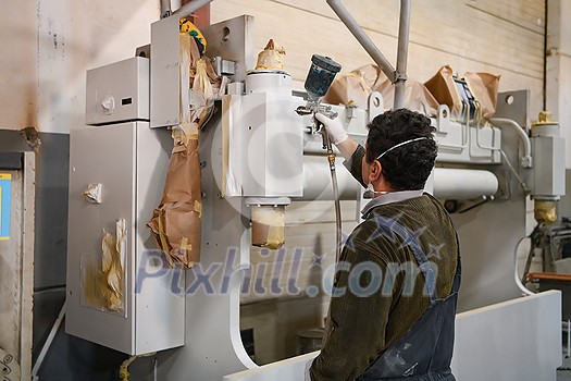 A worker painting to mechanical part with airless spray. High quality photo A worker painting to mechanical part with airless spray. High quality photo