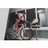 Man cycling on the machine trainer he is exercising in the home at night. Playing online bike racing game during coronavirus covid19 lockdown. New normal concept.