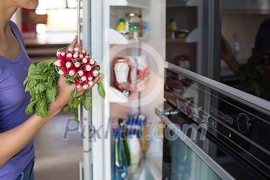 Pretty, young woman taking fresh vegetables from her fridge - being on a gluten free vegan diet does not seem to be a problem for her (shallow DOF; color toned image) Pretty, young woman taking fresh vegetables from her fridge - being on a gluten free vegan diet does not seem to be a problem for her (shallow DOF; color toned image)