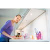 Pretty, young woman cleaning her modern kitchen after cooking lunch (shallow DOF; color toned image)