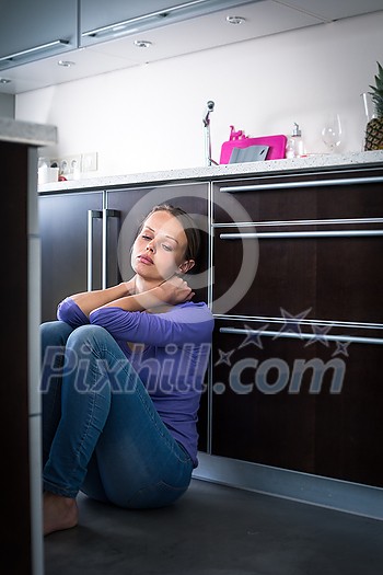 Depressed young woman, sitting on the kitchen floor, feeling down Depressed young woman, sitting on the kitchen floor, feeling down