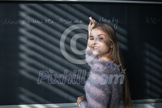 Pretty, young female student in front of a blackboard during math class Pretty, young female student in front of a blackboard during math class