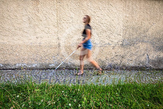 Blind woman walking on city streets, using her white cane to navigate the urban space better and to get to her destination safely Blind woman walking on city streets, using her white cane to navigate the urban space better and to get to her destination safely