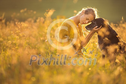 Pretty, young woman with her large black dog on a lovely sunlit meadow in warm evening light, playing together Pretty, young woman with her large black dog on a lovely sunlit meadow in warm evening light, playing together
