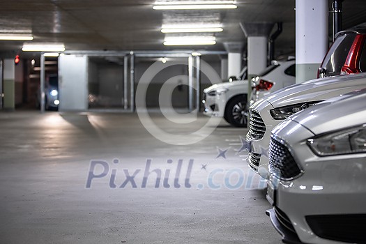 Underground parking. Cars parked in a garage with no people. Many cars in parking garage interior. Underground parking with cars (color toned image) Underground parking. Cars parked in a garage with no people. Many cars in parking garage interior. Underground parking with cars (color toned image)