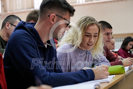 In the Classroom Multi Ethnic Students Listening to a Lecturer and Writing in Notebooks. Smart Young People Study at the College. In the Classroom Multi Ethnic Students Listening to a Lecturer and Writing in Notebooks. Smart Young People Study at the College.