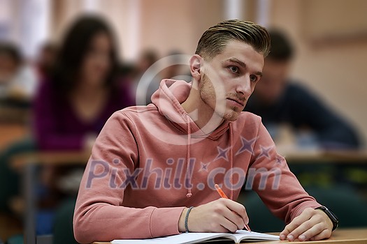 student taking notes while studying in high school. Portrait of college guy writing while completing assignment. student taking notes while studying in high school. Portrait of college guy writing while completing assignment.