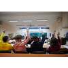 a large group of students raises their hand to answer a question asked by the professor