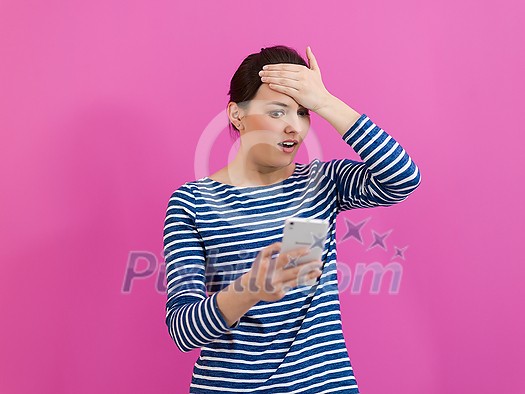 a disappointed-faced girl looks at her cell phone as she stands in front of a pink background
a disappointed-faced girl looks at her cell phone as she stands in front of a pink background