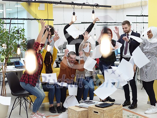 Group of business people having party and  throwing paper in air at modern coworking open space  startup office