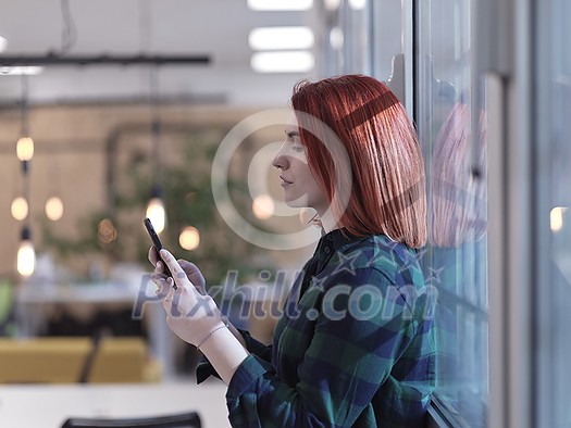 redhead business woman as influencer in creative modern coworking startup open space office using smart phone redhead business woman as influencer in creative modern coworking startup open space office using smart phone