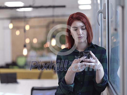redhead business woman as influencer in creative modern coworking startup open space office using smart phone