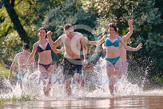 Summer joy group of happy friends having fun while running and splashing on river Summer joy group of happy friends having fun while running and splashing on river