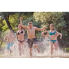 Summer joy group of happy friends having fun while running and splashing on river