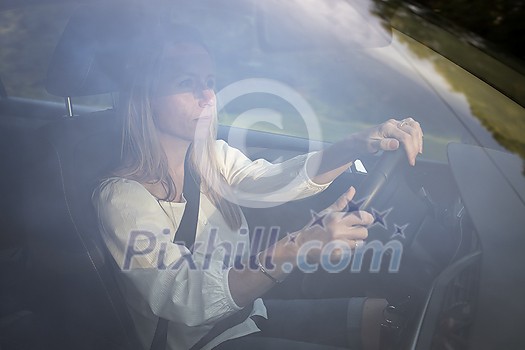 Pretty midle aged woman at the steering wheel of her car, going fast Pretty midle aged woman at the steering wheel of her car, going fast