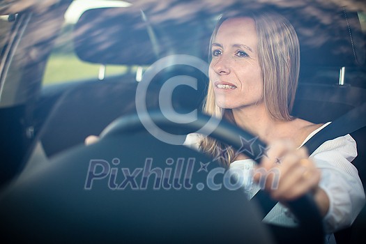 Pretty middle aged woman at the steering wheel of her car Pretty middle aged woman at the steering wheel of her car