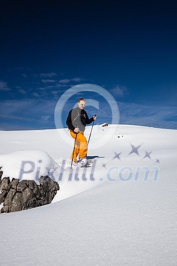 Winter sports - young man walking with snowshoes uphill in high mountains covered with lots of snow (selective focus on the mountain in the background) Winter sports - young man walking with snowshoes uphill in high mountains covered with lots of snow (selective focus on the mountain in the background)