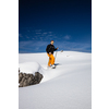 Winter sports - young man walking with snowshoes uphill in high mountains covered with lots of snow (selective focus on the mountain in the background)