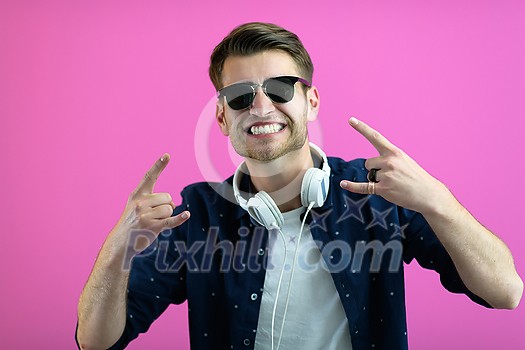 the guy wears glasses and headphones while dancing and having fun isolated on a pink background
the guy wears glasses and headphones while dancing and having fun isolated on a pink background