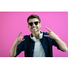 the guy wears glasses and headphones while dancing and having fun isolated on a pink background
