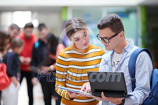 Two students using modern technology stand in the hallway while waiting for classes to begin Two students using modern technology stand in the hallway while waiting for classes to begin