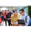 Two students using modern technology stand in the hallway while waiting for classes to begin