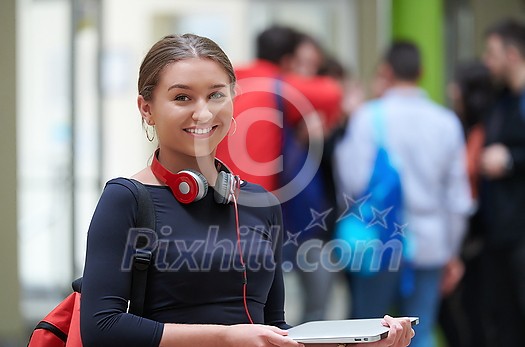 portrait of a happy young student getting ready for class while waiting in the college hallway with headphones and laptop portrait of a happy young student getting ready for class while waiting in the college hallway with headphones and laptop