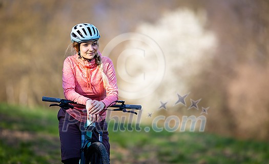 Pretty, young woman with her mountain bike going for a ride past the city limits, getting the daily dose of cardio Pretty, young woman with her mountain bike going for a ride past the city limits, getting the daily dose of cardio