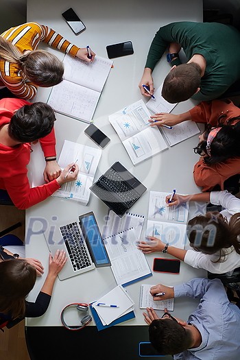 Top view of university students sitting at a table studying and working on laptop Top view of university students sitting at a table studying and working on laptop