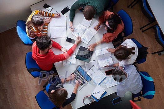 Top view of university students sitting at a table studying and working on laptop