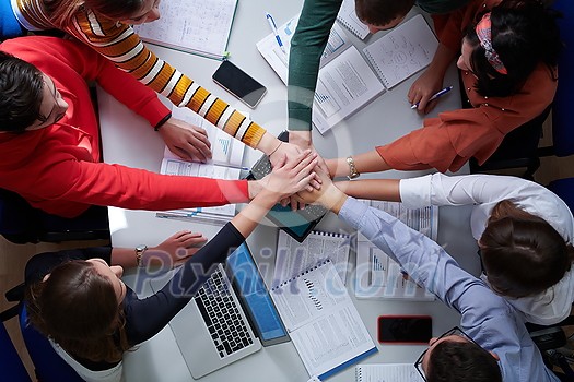 Group of young students in electronics classroom celebrating successfully finished project with holding their hands together, education and technology concept Group of young students in electronics classroom celebrating successfully finished project with holding their hands together, education and technology concept
