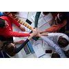 Group of young students in electronics classroom celebrating successfully finished project with holding their hands together, education and technology concept