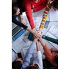 Group of young students in electronics classroom celebrating successfully finished project with holding their hands together, education and technology concept