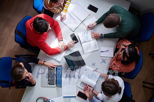 Top view of university students sitting at a table studying and working on laptop Top view of university students sitting at a table studying and working on laptop