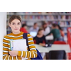a portrait of a girl holding a notebook in her hand while standing in front of the library