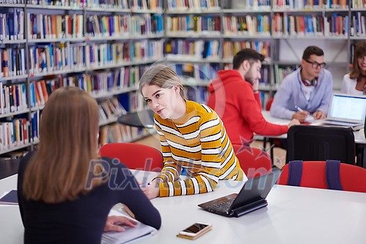 a group of students sit in a library and create a project for a school with the help of modern technology