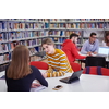 a group of students sit in a library and create a project for a school with the help of modern technology