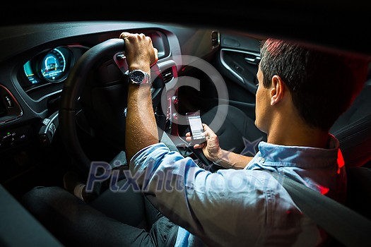 Driving a car at night - young man driving his modern car at night, in a city (shallow DOF; color toned image) Driving a car at night - young man driving his modern car at night, in a city (shallow DOF; color toned image)