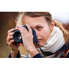 Pretty female amateur photographer taking photos outdoors, doing what she loves to do