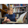 Pretty, young woman studying an old book in archives