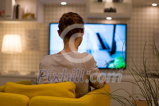 Pretty, young woman watching TV at home (color toned image; shallow DOF) Pretty, young woman watching TV at home (color toned image; shallow DOF)