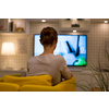 Pretty, young woman watching TV at home (color toned image; shallow DOF)