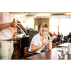 Cute female restaurant customer with wine waiter choosing the right wine for her to go well with the food