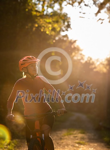 Pretty, young woman biking on a mountain bike enjoying healthy active lifestyle outdoors in summer (shallow DOF) Pretty, young woman biking on a mountain bike enjoying healthy active lifestyle outdoors in summer (shallow DOF)